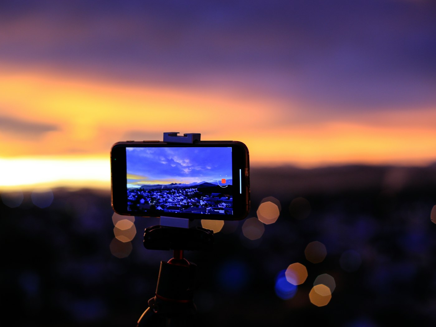 Phone on a tripod filming a sunset over a city